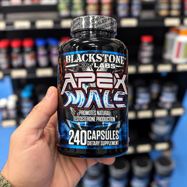 Blackstone Labs Apex Male 240 Capsules bottle being held up with a bunch of supplements in the background.