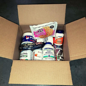 Box containing various health and fitness products including supplements and protein bars.